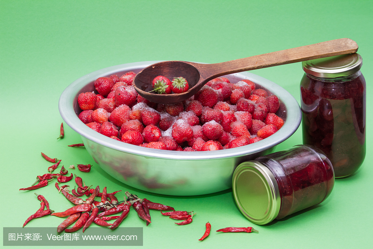 草莓与糖和用于制作果酱的罐子在制造商。